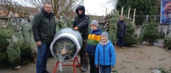 Luca, Till und Roman Hartmann beim Weihnachtsbaumkauf. Lehrer Frank Löhr verpackt den Baum fachmännisch in einem Netz.